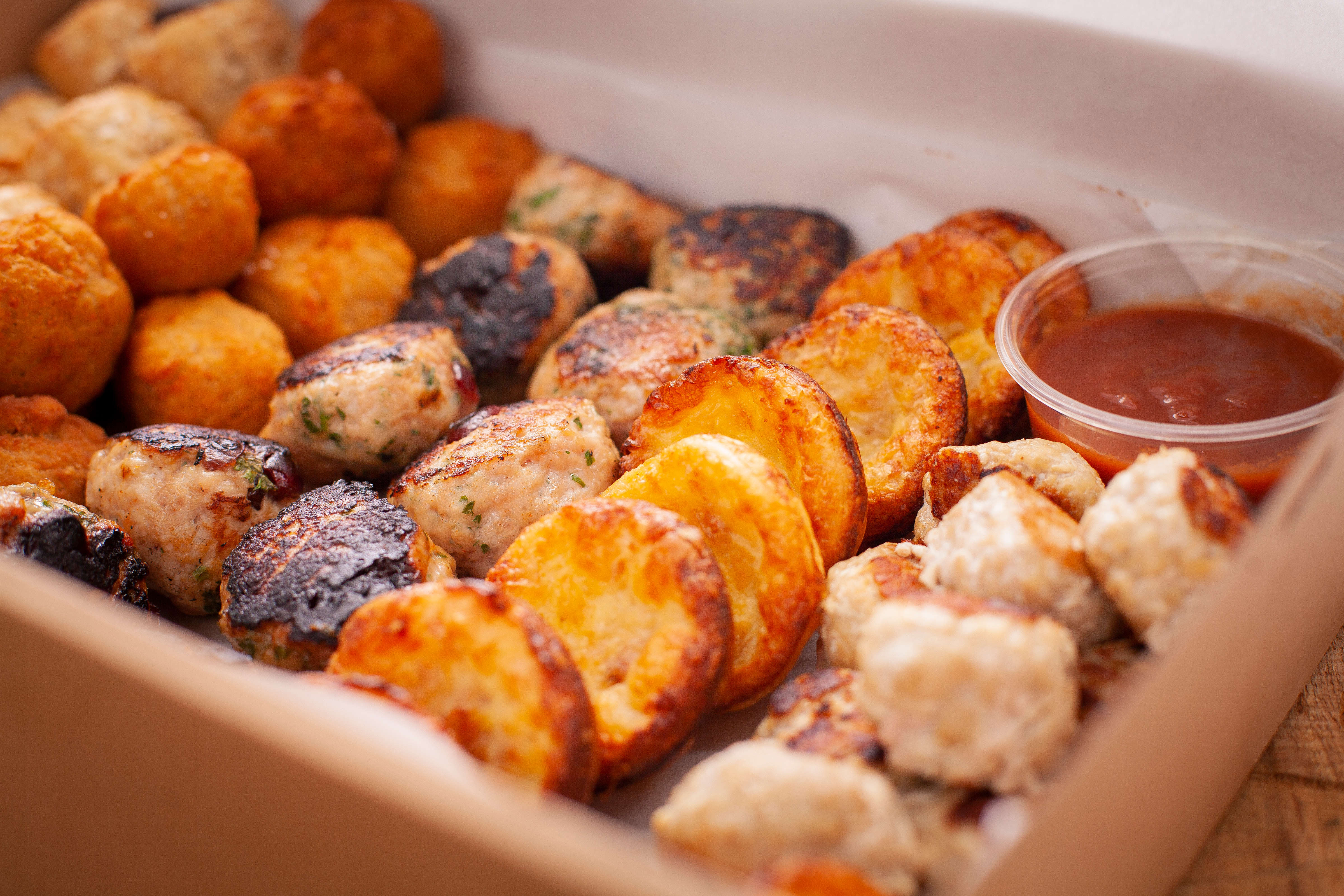 Hot savoury box containing 50 items – sausage rolls, chicken balls, smoked salmon arancini, bacon and cheese tartlets, meatballs. Photo: Richard Jupe.