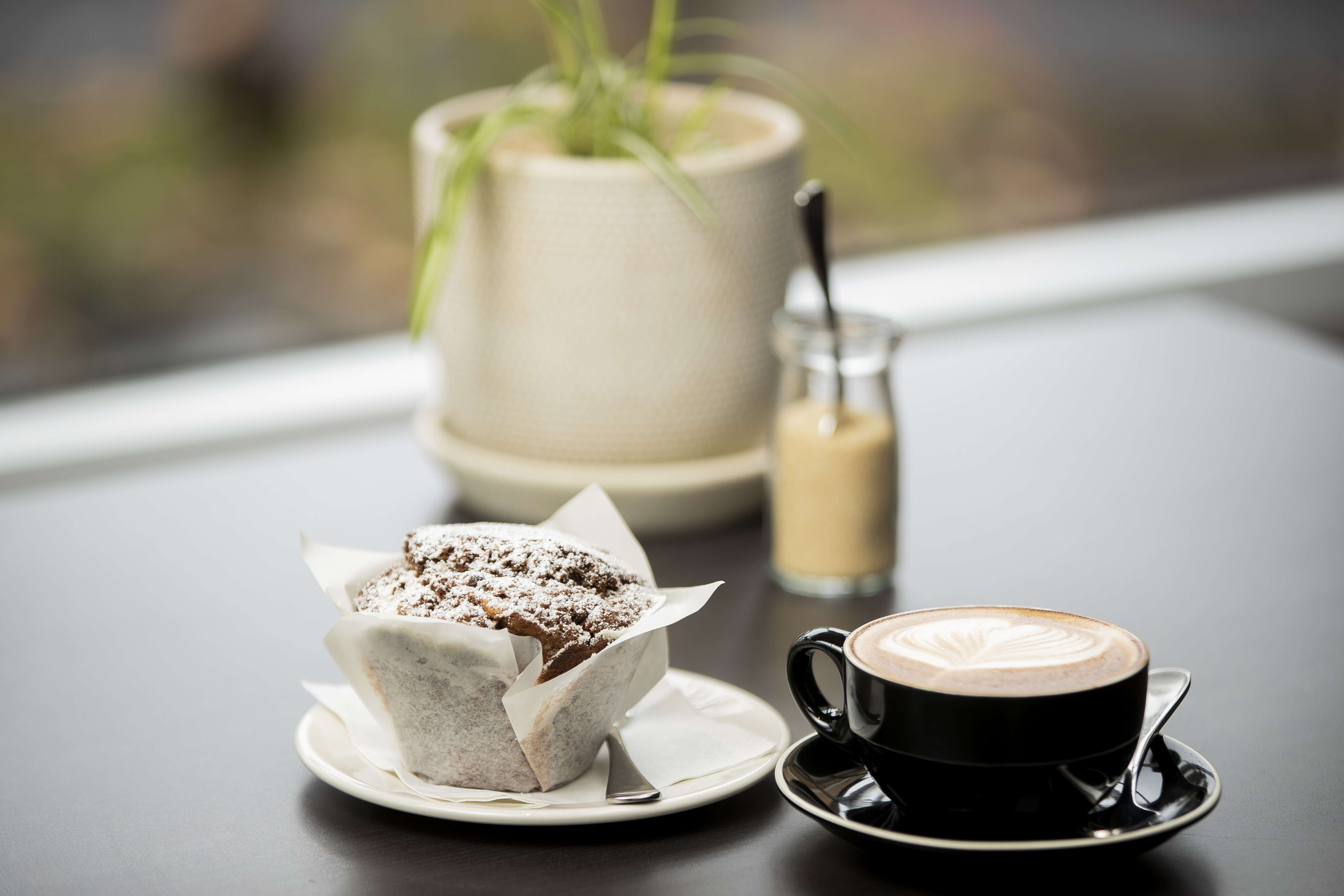 Flat white coffee and a chocolate muffin on a table. Photo: Richard Jupe.
