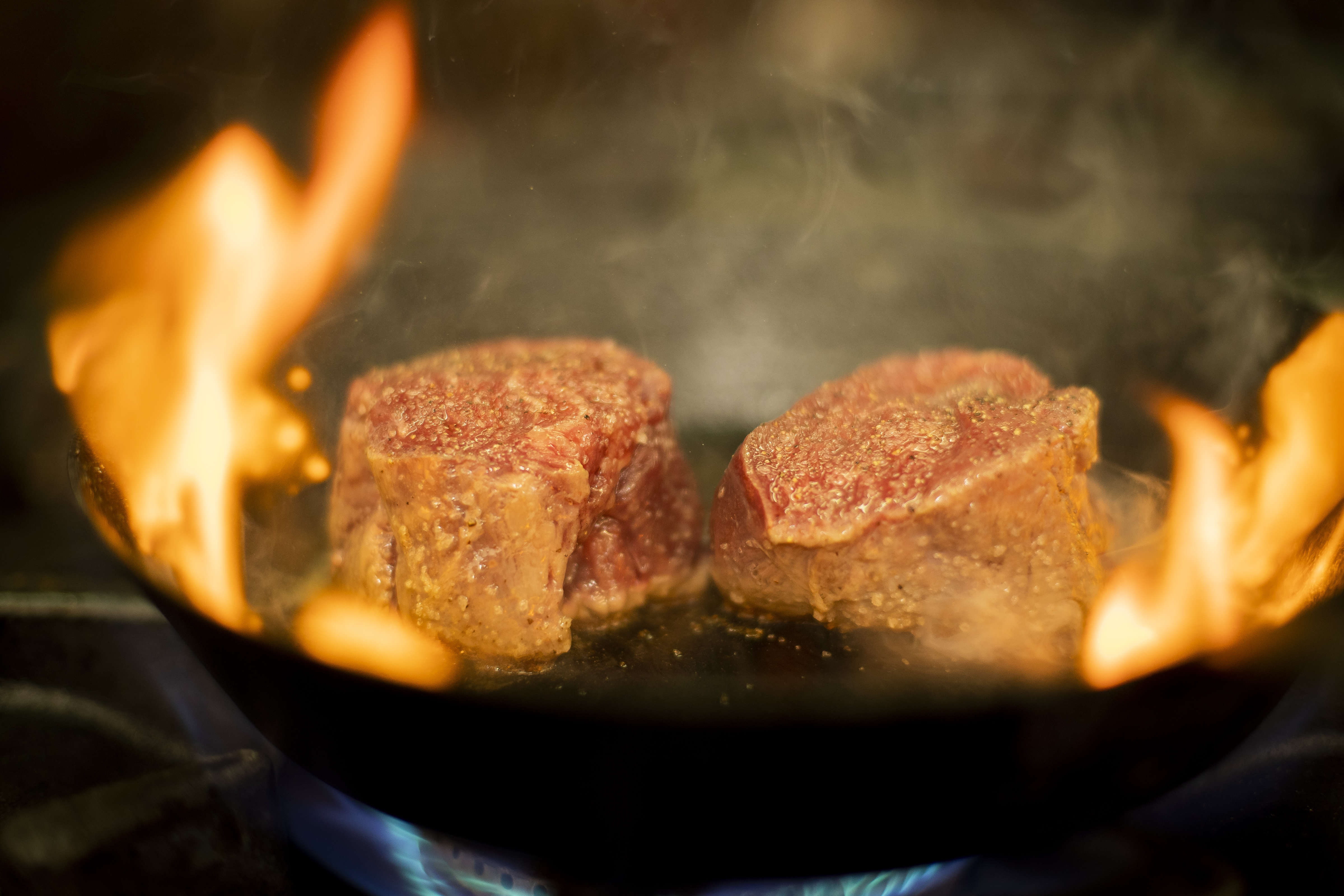 Close up of eye fillet steak in a pan frying with flames. Photo: Richard Jupe.