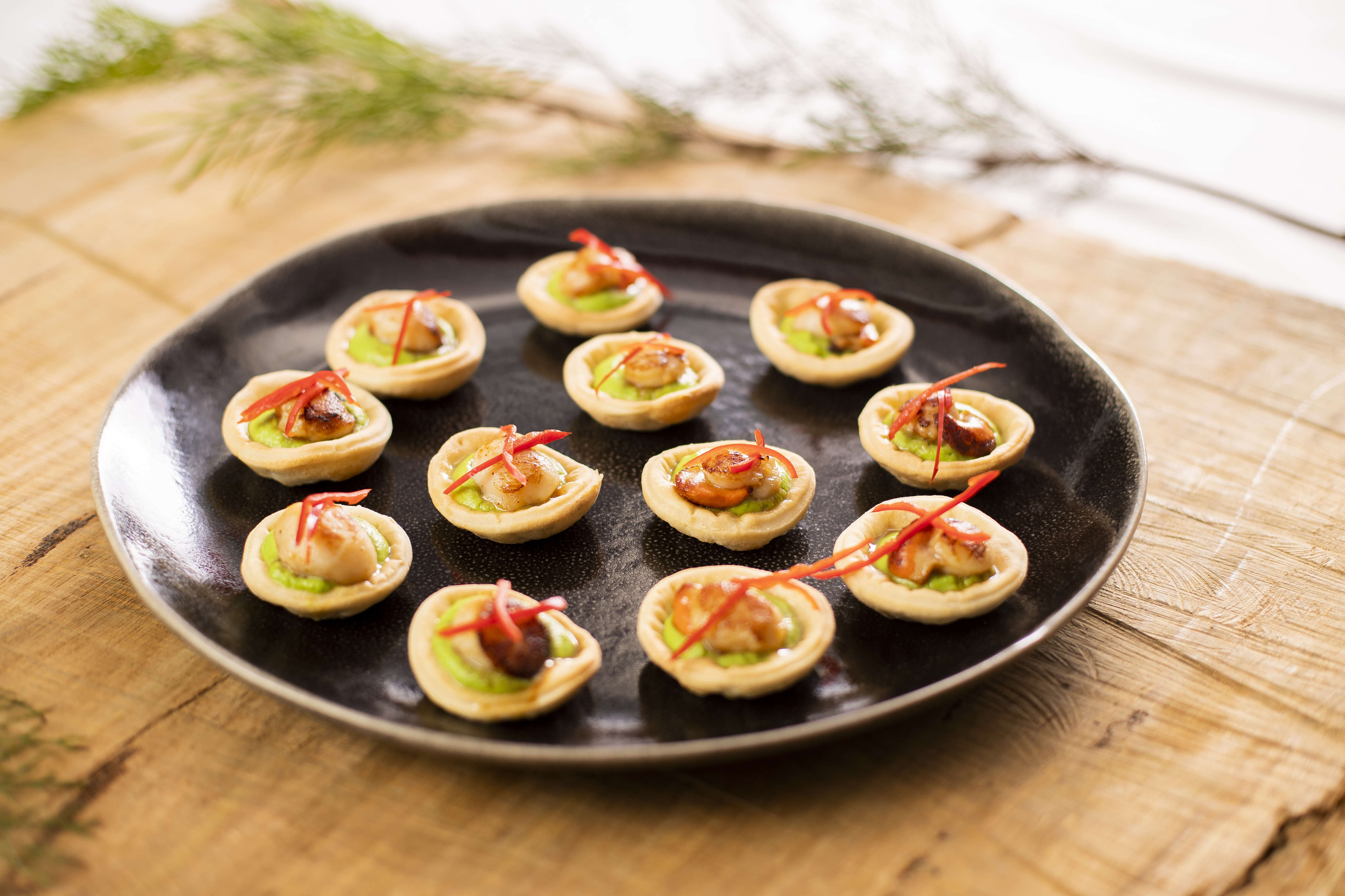 Round platter with tart shells filled with guacamole, panfried scallop, topped with julienne of red capsicum. Photo: Richard Jupe.