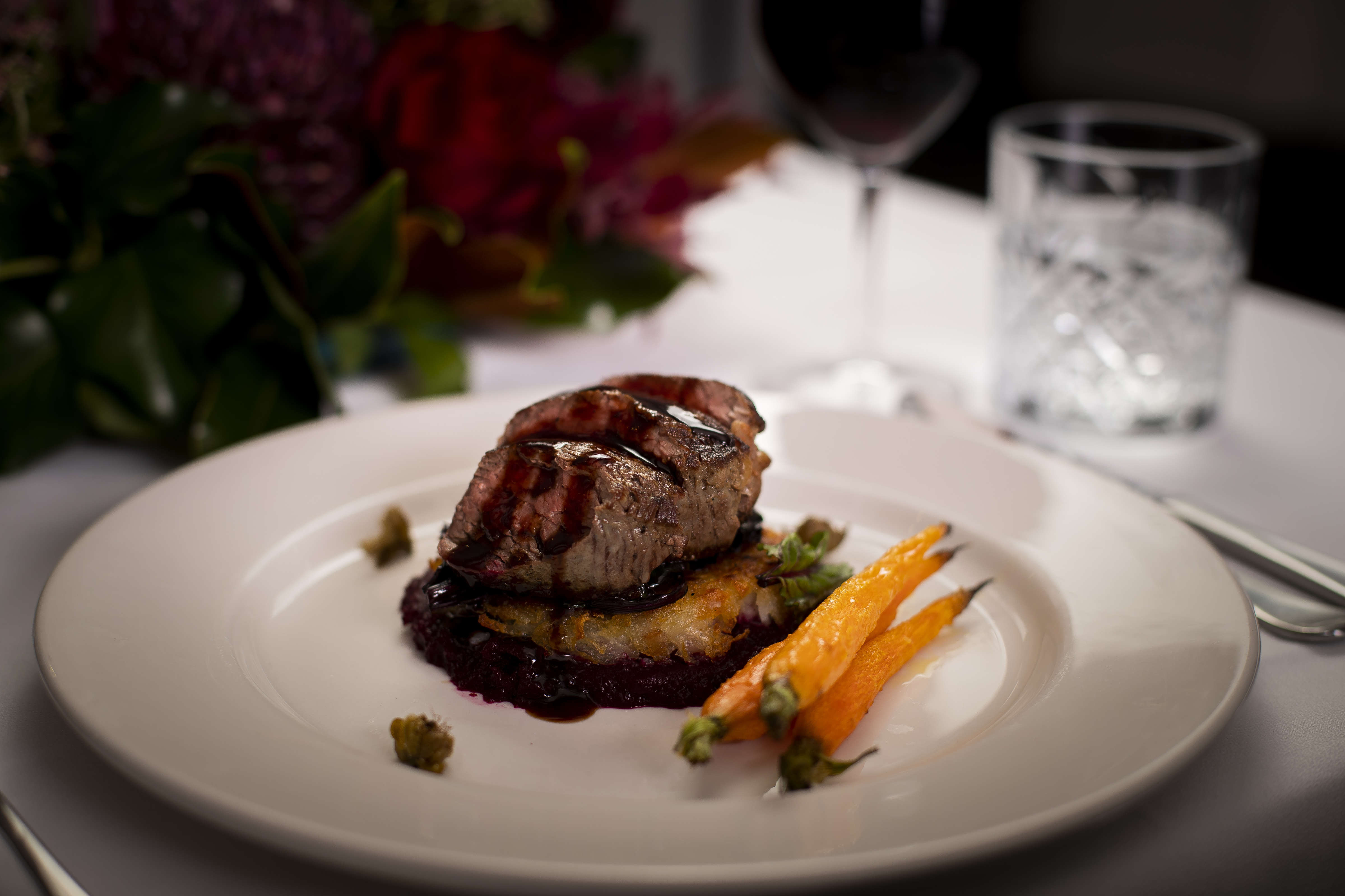 Roasted eye fillet slices on hashbrown with beetroot puree and roast baby carrots glazed with jus on a white dinner plate with fried capers. Photo: Richard Jupe.