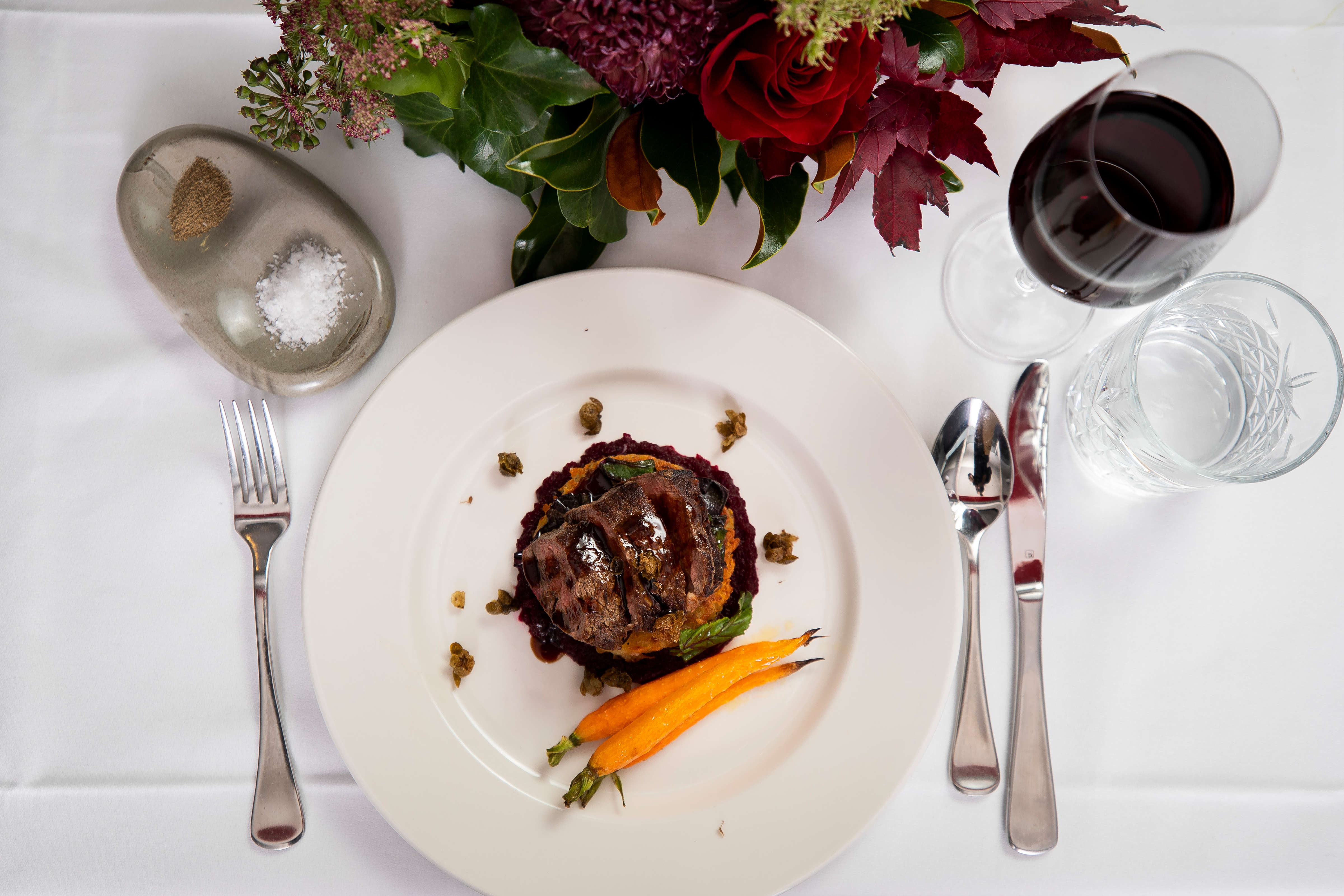Flat lay photo of Roasted eye fillet slices on hashbrown with beetroot puree and roast baby carrots glazed with jus on a white dinner plate with fried capers. Photo: Richard Jupe.