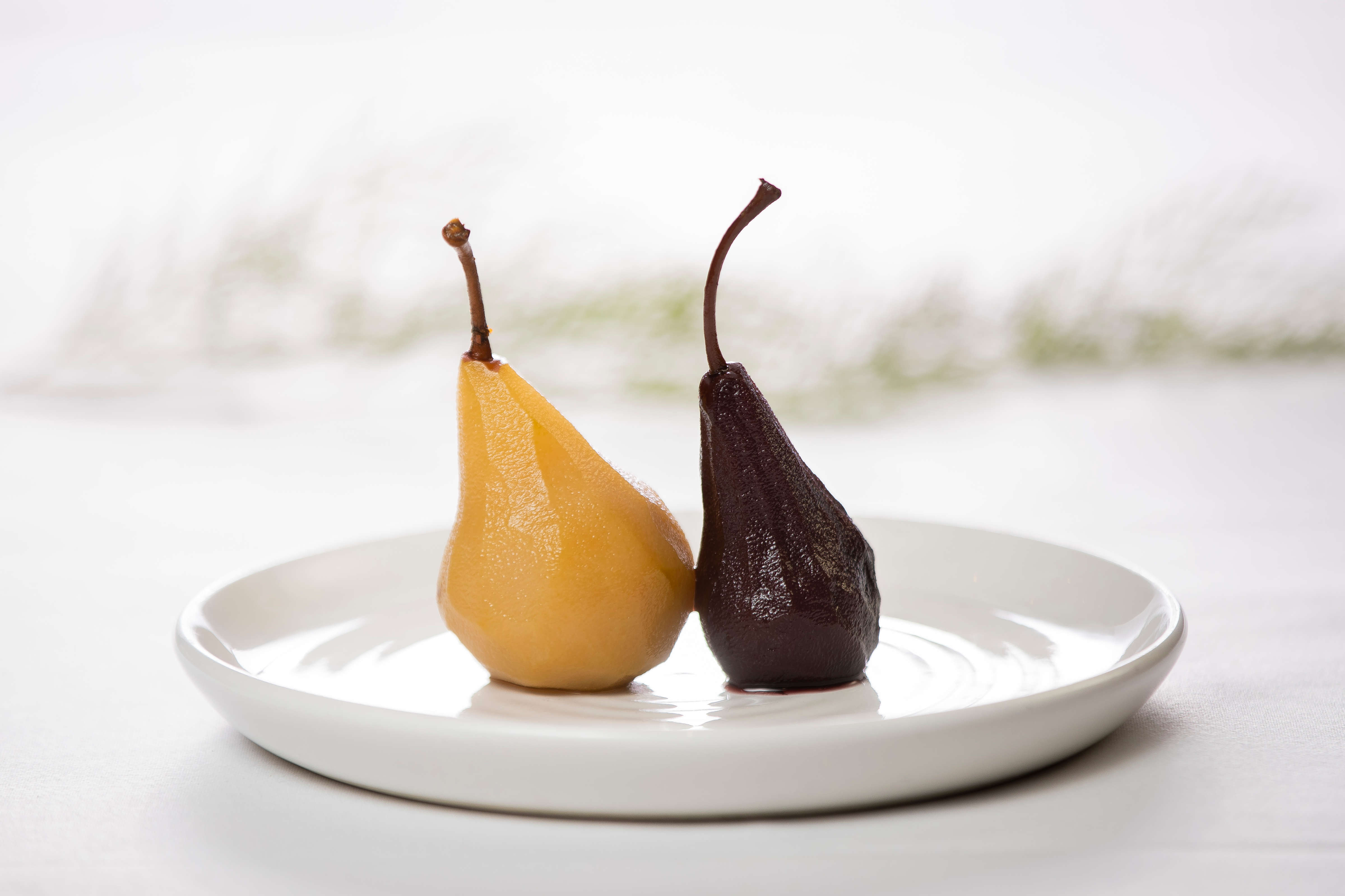 White round plate with one red wine poached pear and one saffron poached pear. Photo: Richard Jupe.