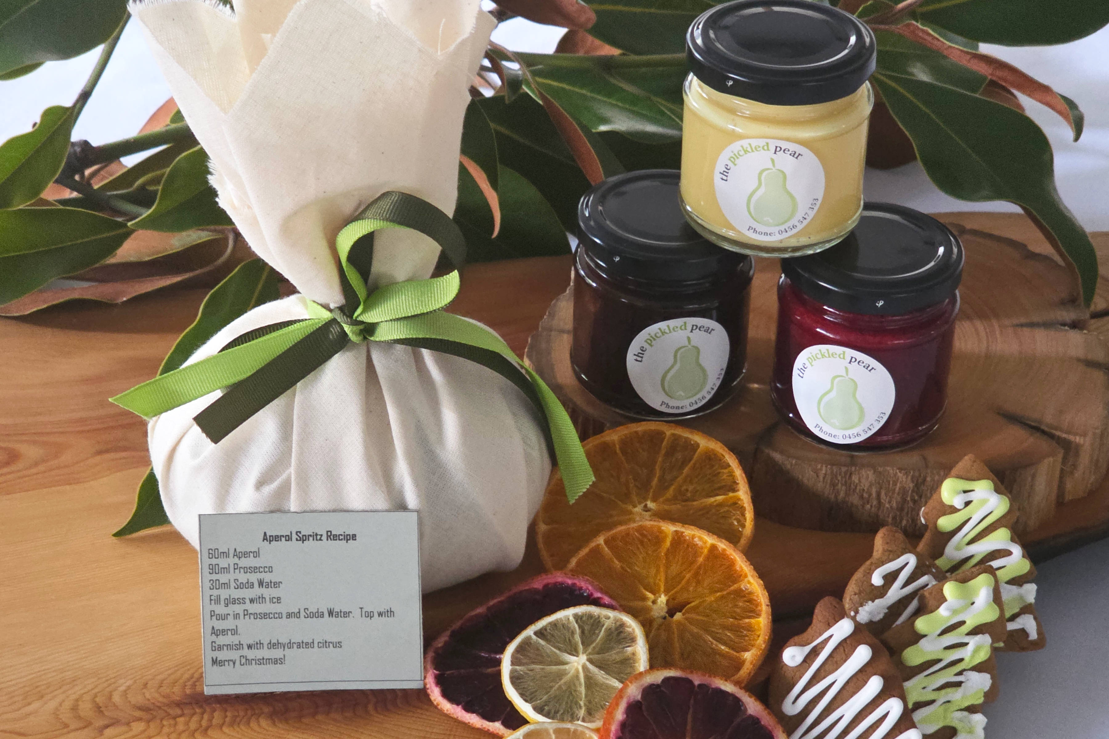 500g Christmas pudding, 100mL jar brandy custard, 100mL jar raspberry coulis, 100mL jar chocolate whisky sauce, Aperol spritz recipe and dehydrated citrus, 2 × gingerbread cookies. Credit: Pickled Pear.