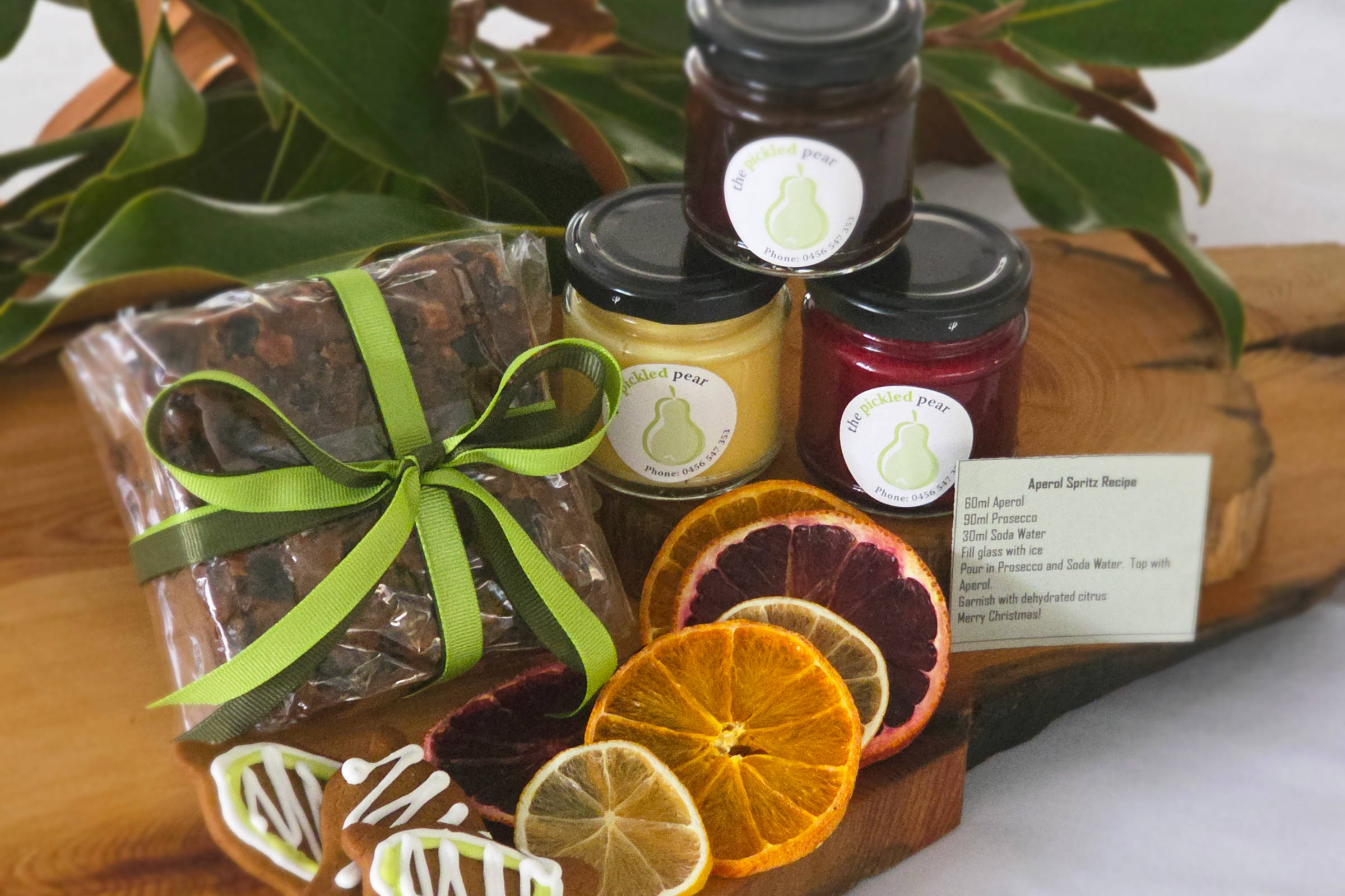 500g Christmas cake, 100mL jar brandy custard, 100mL jar raspberry coulis, 100mL jar chocolate whisky sauce, Aperol spritz recipe and dehydrated citrus, 2 × gingerbread cookies. Credit: Pickled Pear.